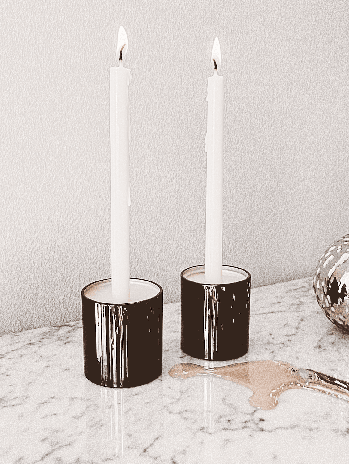 White taper candles in black holders on marble